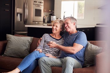 Senior white couple relaxing on couch watching television