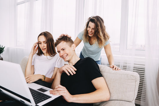 friendship, technology, happiness, leisure, social media, fun concept. Excited friends having fun watching comedy picture online video on laptop together, three millennial people having fun