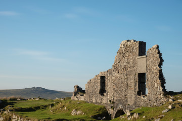 Stunning landscape sunset image over abandoned Foggintor Quarry in Dartmoor with raking soft sunlight over ruins and derelict buildings