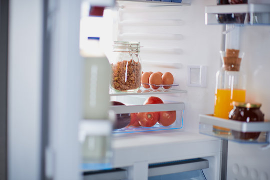 Picture of opened fridge with groceries inside.