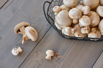 Champignon mushrooms in a basket on a wood background