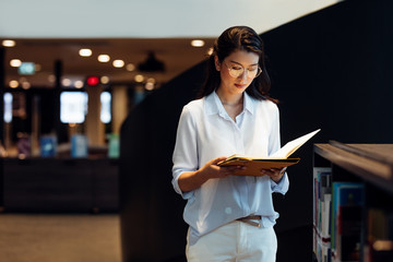 Beautiful Thai businesswoman holding a folder and reading a document.