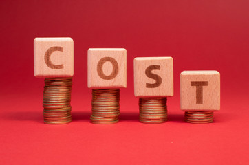 COST word made with wooden blocks with stacked coins: Cost reduction 
