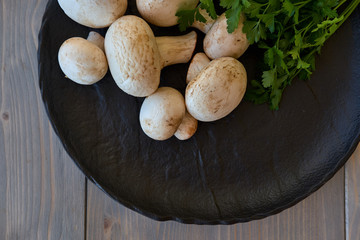 Champignon mushrooms on a black plate with greens