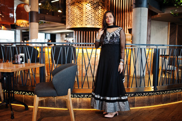 Pretty indian girl in black saree dress posed at restaurant.