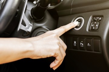 close up of finger pressing the start/stop engine button at a car.