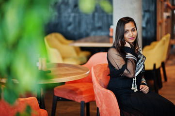 Pretty indian girl in black saree dress posed at restaurant.