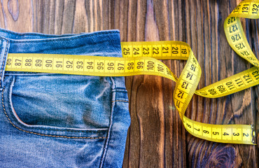 denim pants, centimeter on wooden table background. fitness, diet. weight.