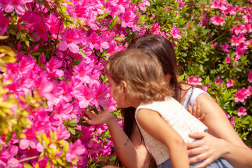 Obraz na płótnie Canvas daughter with mother near the bush of flowers