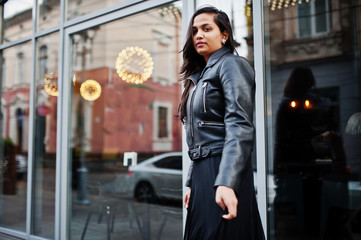 Obraz premium Pretty indian girl in black saree dress and leather jacket posed outdoor at street.