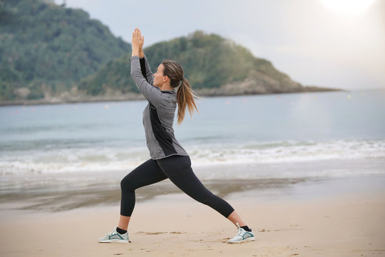 Woman doing yoga on a beach in sportswear