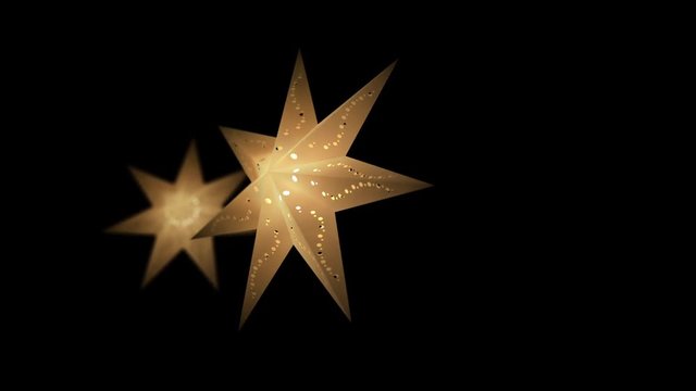 Two christmas star paper lanterns shining and glowing with warm light in yellow color on a black background. Shallow depth of field. Stars slowly rotate. 3D rendered tracking shot from right to left. 