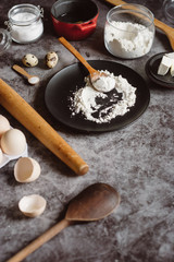Ingredients and utensils for baking. Spoon with flour, dishes, eggs,  butter salt and rolling pin on a grey background. Flat lay. Text space