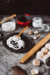 Ingredients and utensils for baking. Spoon with flour, dishes, eggs,  butter salt and rolling pin on a grey background. Flat lay. 