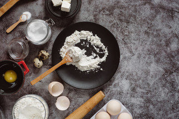 Ingredients and utensils for baking. Spoon with flour, dishes, eggs,  butter salt and rolling pin on a grey background. Flat lay. Text space