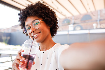 Smiling woman posing for a selfie with a drink in her hand