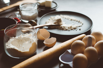 Ingredients and utensils for baking. Spoon with flour, dishes, eggs,  butter salt and rolling pin on a grey background. Flat lay. 