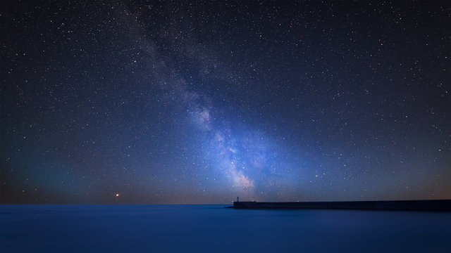 ibrant Milky Way composite image over landscape of Stunning long exposure of lighthouse