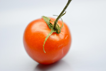 cherry tomato with stem on a red background