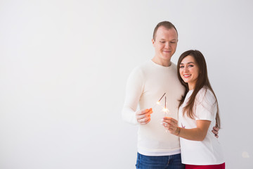 Valentine's Day concept - Young happy smiling cheerful attractive couple celebrating with sparklers on white background with copy space