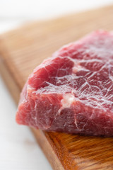 Morning in the kitchen. Raw meat. Raw fresh beef steak on a wood cutting board. White wooden background, top view, copy space, Daylight