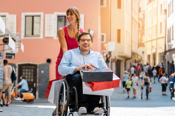 Mann im Rollstuhl mit Freundin beim Einkaufen in der Stadt