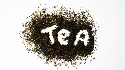 The tea particles are scattered on the table. White background. The view from the top. Inscription tea. Concept. Abstraction. Art. Isolated.