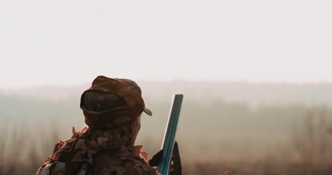 Hunter aims the target with hunting rifle in sunset light