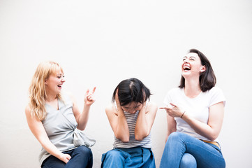 Cupple caucasian women laughing and looking asian woman ,who confused and take their hands off the head, insolvent business ,unsuccessful business concept.