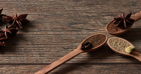 Cardamom, cloves, star anise. Ground spices in wooden spoons.Different types of whole Indian spices in wooden background close-up. Healthy food.