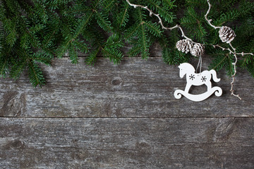 Christmas wooden background with spruce branches, cones and decor horse