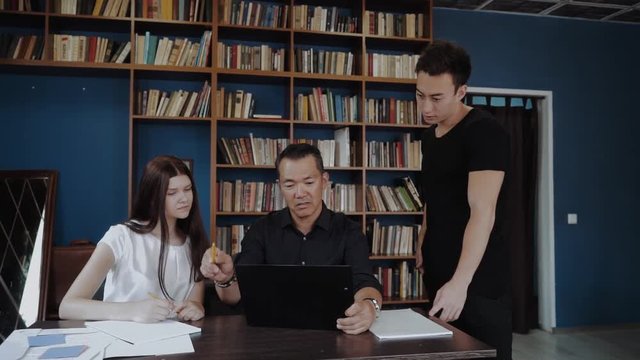 Group of multi ethnic students, groupmates spend time with teacher, lecturer, professor. Students, scientists studying after classes, professor , teaches , explaining in library