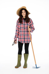 Young farmer with shears and hoe in hands, she is wearing a straw hat, checked shirt and green rubber boots