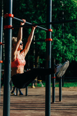 Picture curly blonde sports pulls up on sports simulator in park