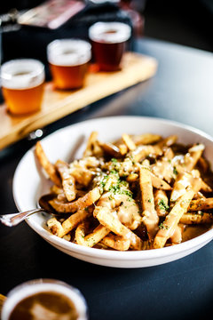 Bowl of poutine with pint glasses