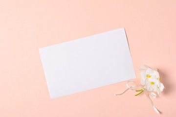 Bouquet of violet flowers (viola) and empty greeting card on pink paper background. Valentine's day celebration concept. Top view. Flat lay. Mock-up