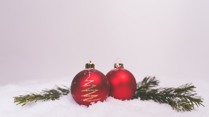 Fototapeta na wymiar Weihnachten Weihnachtsdeko rote Kugeln im Schnee weißer Hindtergund