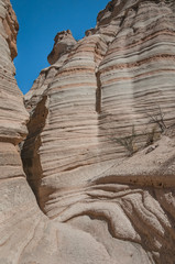 Entrance to a small slot canyon in sculpted rock cliffs with pink and gray stripes 
