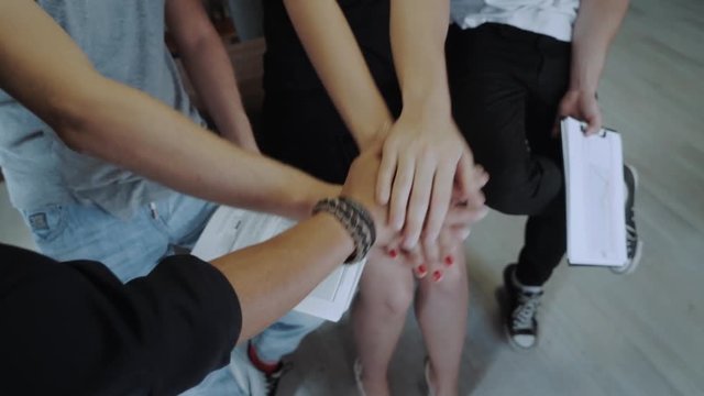 Multiethnic group of young people putting their hands on top of each other. Close up image of young students making a stack of hands.