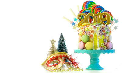 Happy New Year's candy land lollipop drip cake with 2019 candles on white background.
