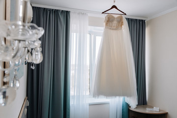 Wedding dress hanging on a hanger on the window