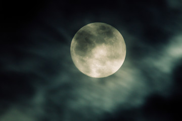 mystic full moon in the sky behiond some clouds or mist