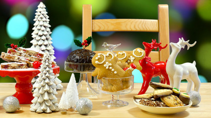 Festive table with traditional English and European style Christmas food including panforte cake, plum pudding, gingerbread cookies, and chocolate covered shortbread.