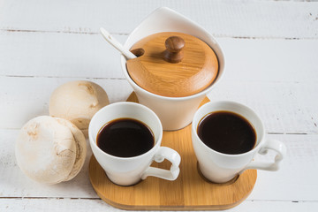Marshmallow with marmalade, jug of milk, coffee in cup and sugar, spoon on wooden table