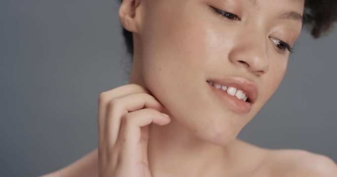 close up portrait beautiful mixed race woman touching soft skin with hand caressing smooth healthy complexion enjoying natural skincare gorgeous feminine beauty concept on grey background