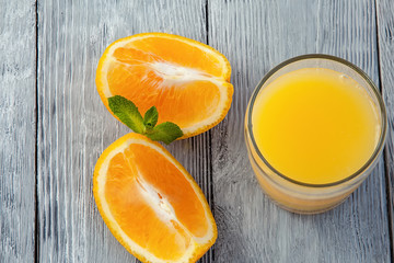 glass of orange juice and orange slices on wooden background