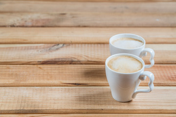 coffee creamers. two cups of coffee on a wooden table.