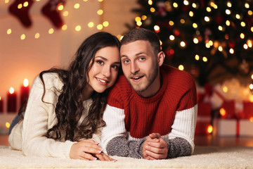 Young couple lying at home near christmas tree