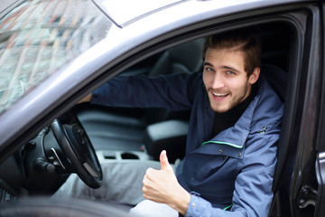 young man showing thumb up,sitting at the wheel of a new car