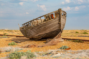 A falling apart fishing boat on a pebble beach in Kent